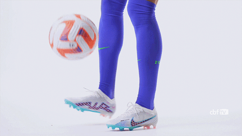 a woman wearing a blue shirt and white shorts kicks a soccer ball