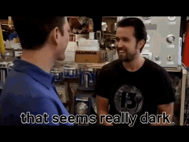 a man in a black shirt with the number 13 on it talks to another man