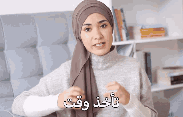 a woman wearing a head scarf and a sweater with arabic writing