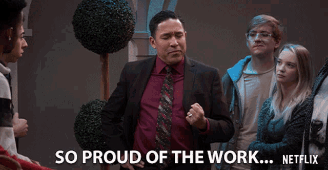 a man in a suit and tie stands in front of a group of people and says so proud of the work netflix