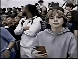 a boy is holding a cell phone in a crowd of people