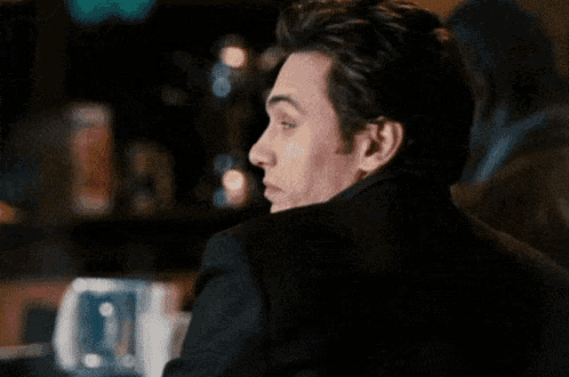 A man turns and gives a knowing wink at a dinner table.
