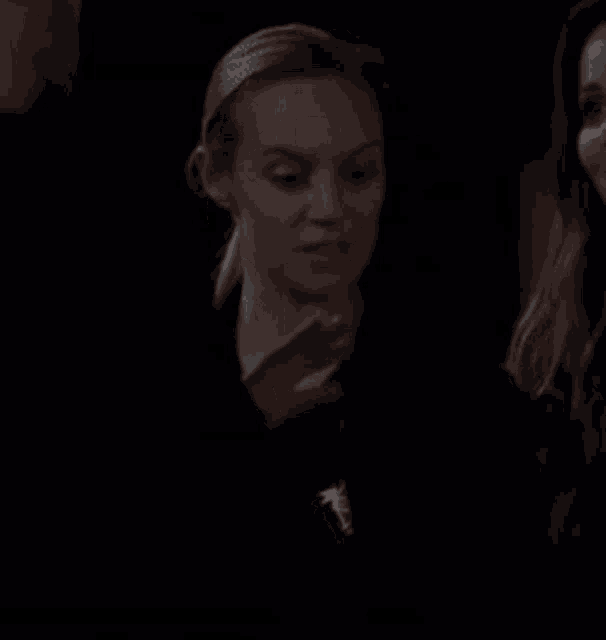 a woman is standing in a dark room with her eyes closed and a man is standing behind her .