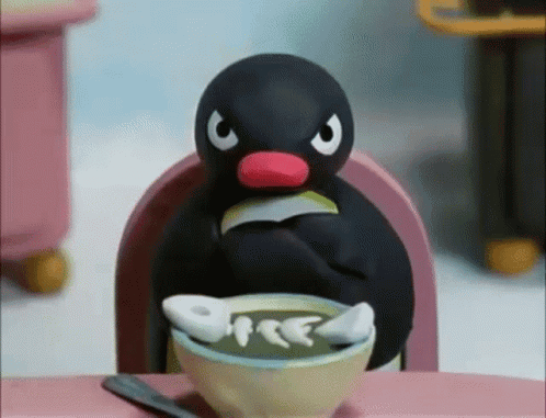 Pingu sits at a table glaring over a bowl of food.