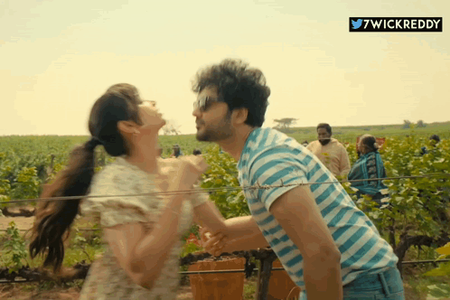 a man in a blue and white striped shirt is carrying a woman on his shoulders
