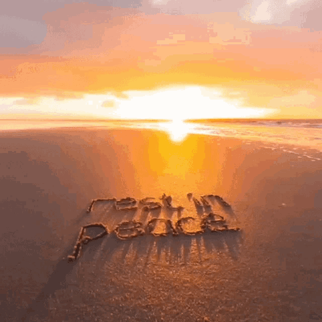 the word peace is written in the sand on the beach at sunset