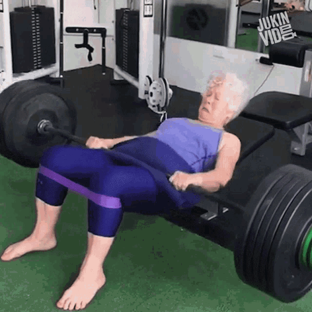 an elderly woman is lifting a barbell with a resistance band around her waist