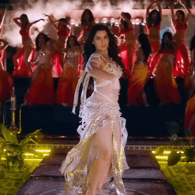 a woman in a white and gold dress is dancing on stage