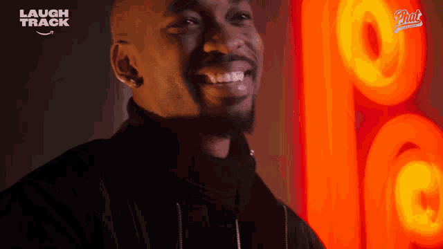 a man is smiling in front of a sign that says " laugh track "