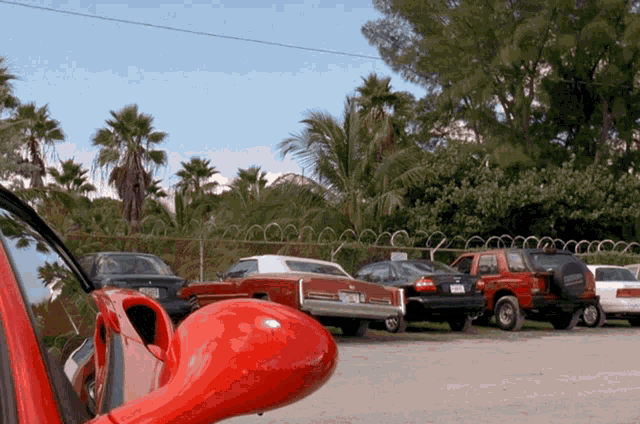 a red car is parked in a parking lot with other cars behind it