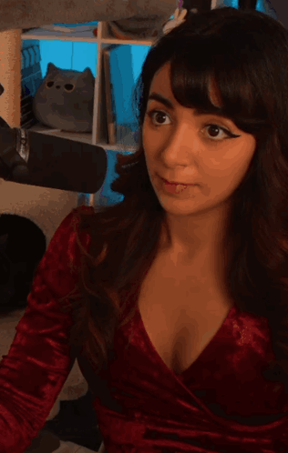 A woman in red looks toward the camera with a surprised expression.