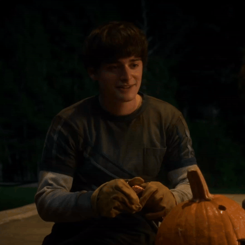 a man is holding a pumpkin and the words you 're welcome are behind him
