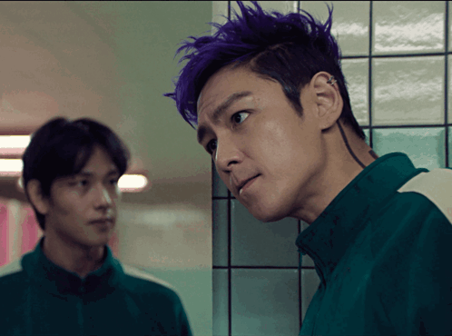 a man with purple hair is standing next to another man in a green shirt