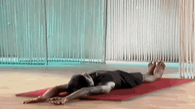 a man is laying on a yoga mat with his legs crossed .