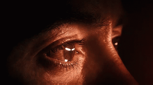 A close-up of Iron Man’s tearful eye in warm light.