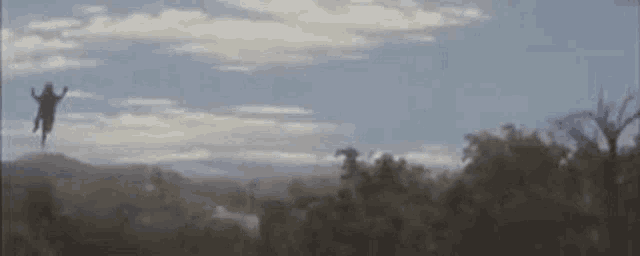 a person is flying through the air over a field with trees in the background .