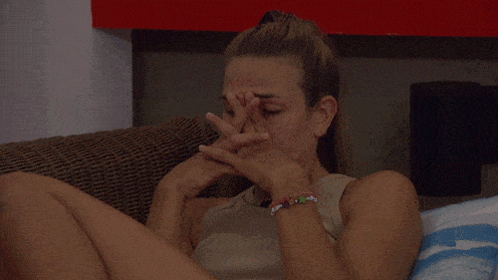 A woman on Big Brother rests her face in her hand, looking emotionally drained.