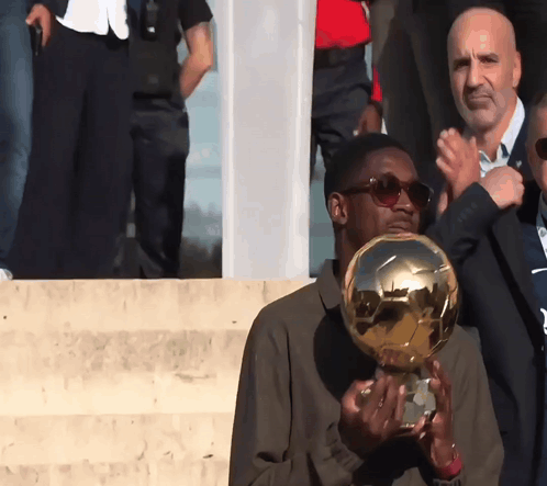 a man in sunglasses holds a trophy in his hand