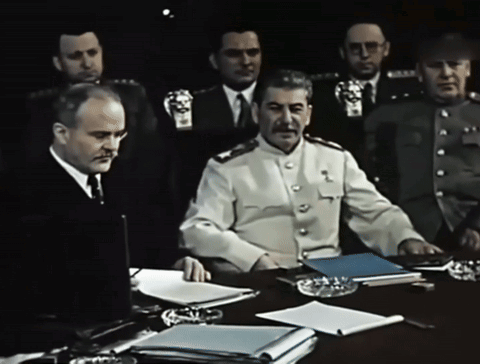 a group of men are sitting around a table with one man wearing a badge that says ' s.s. stalin '