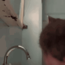 a close up of a person standing next to a faucet