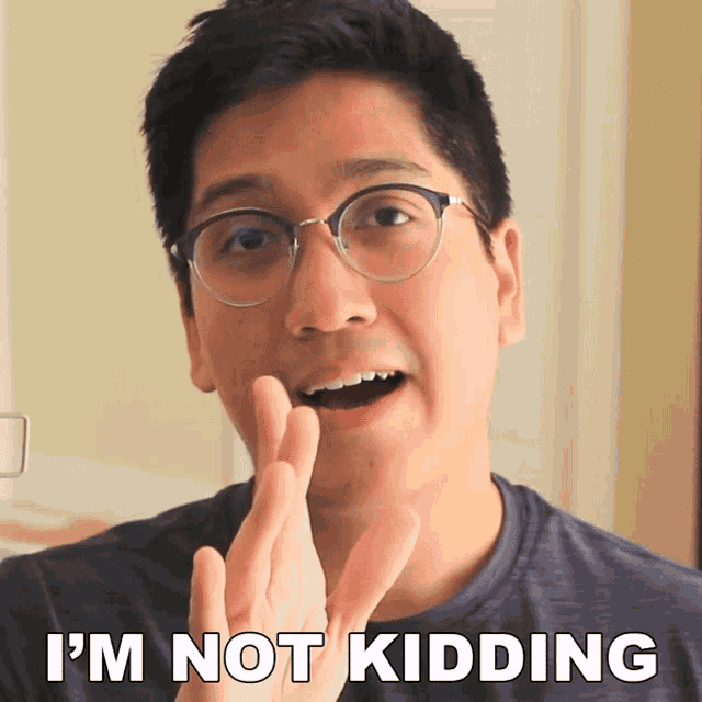 a man with glasses says i 'm not kidding with his fingers crossed