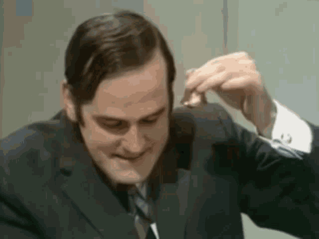 a man in a suit and tie is sitting at a table eating a piece of meat .