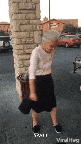 A person in a skirt does a small celebratory dance outside a storefront.