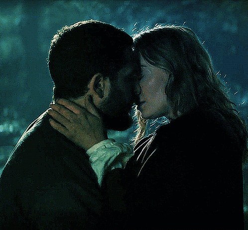 Sophie Turner and Kit Harington kiss closely in a dark teal-lit scene.