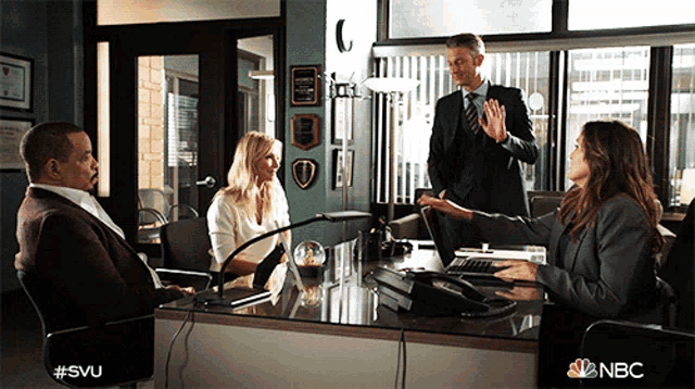 a group of people sitting around a desk with a nbc logo on the bottom
