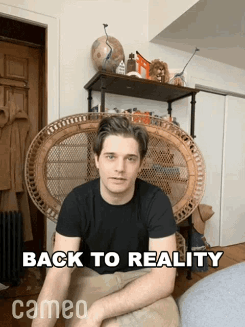 a man sits in a wicker chair with the words back to reality behind him