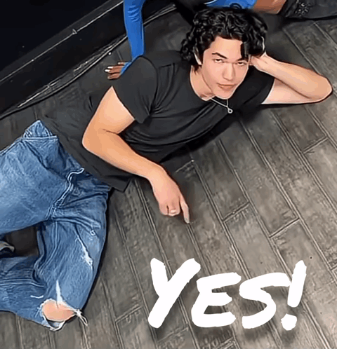 A person lies on the floor and emphatically gestures “YES!”