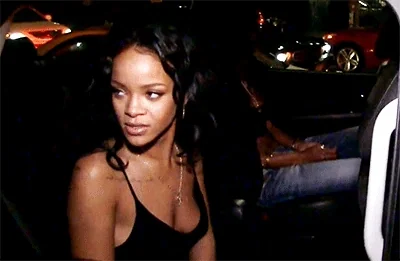 Rihanna raises a car window with an uninterested expression.