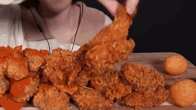 a woman is eating a bunch of fried chicken on a cutting board .