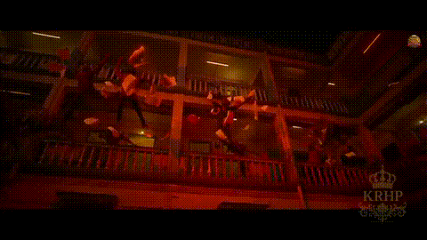 a group of people are standing on a balcony in a dark room with krhf written on the bottom of the screen .