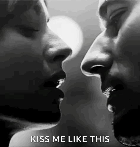 a black and white photo of a man and woman kissing each other .