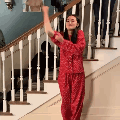 a woman in a red pajamas is standing on a set of stairs .