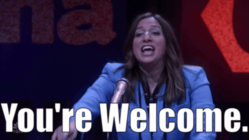 a woman stands in front of a microphone with the words you 're welcome behind her
