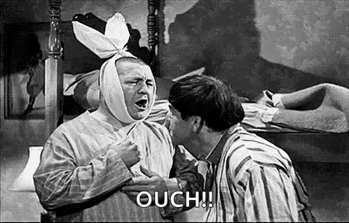 a man with a bandage on his head is being kissed by another man in a black and white photo .
