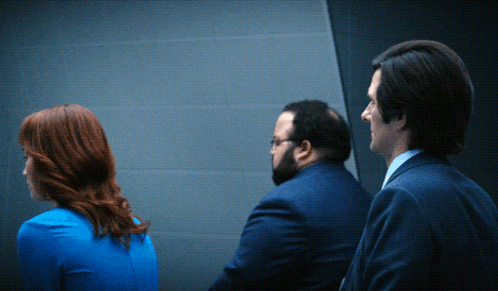 a woman in a blue dress is standing between two men in suits