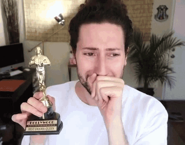 a man is crying while holding a hollywood best drama queen award .