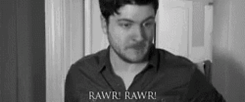 a man in a black shirt is standing in front of a door and says rawr rawr .