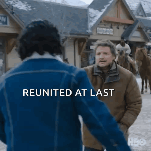 a man in a blue jacket is talking to another man in a brown jacket in a snowy town .