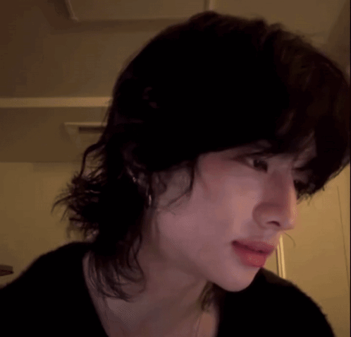 A dark-haired performer looks downward with a subdued, startled expression.