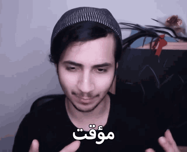 a man wearing a beanie and a black shirt has the word " وقت " written on his face
