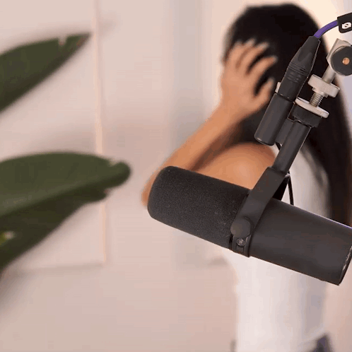 a woman covering her ears in front of a microphone that has the letter o on it
