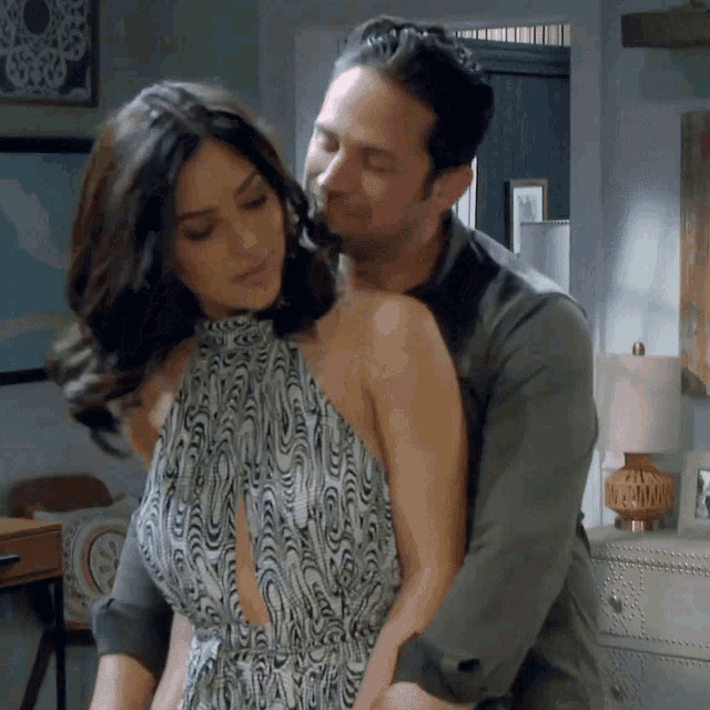 a man is hugging a woman who is wearing a dress