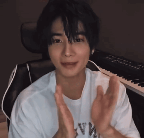 a man wearing a white shirt with the letter v on it is clapping his hands
