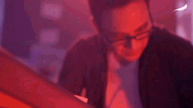 a man wearing glasses is using a laptop computer in a dark room