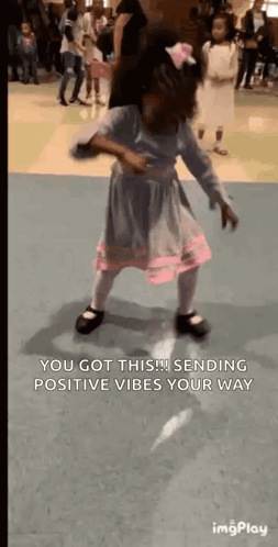 a little girl in a dress is dancing in a dance studio .