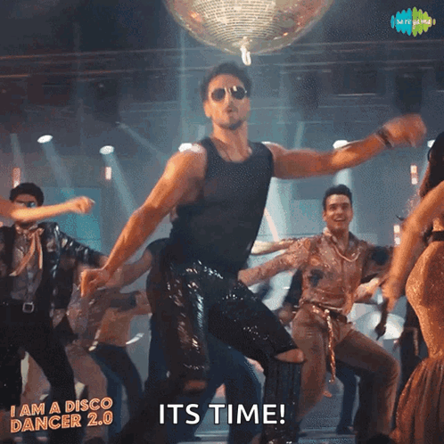 A man in sunglasses strikes a triumphant dance pose onstage with “IT'S TIME!”